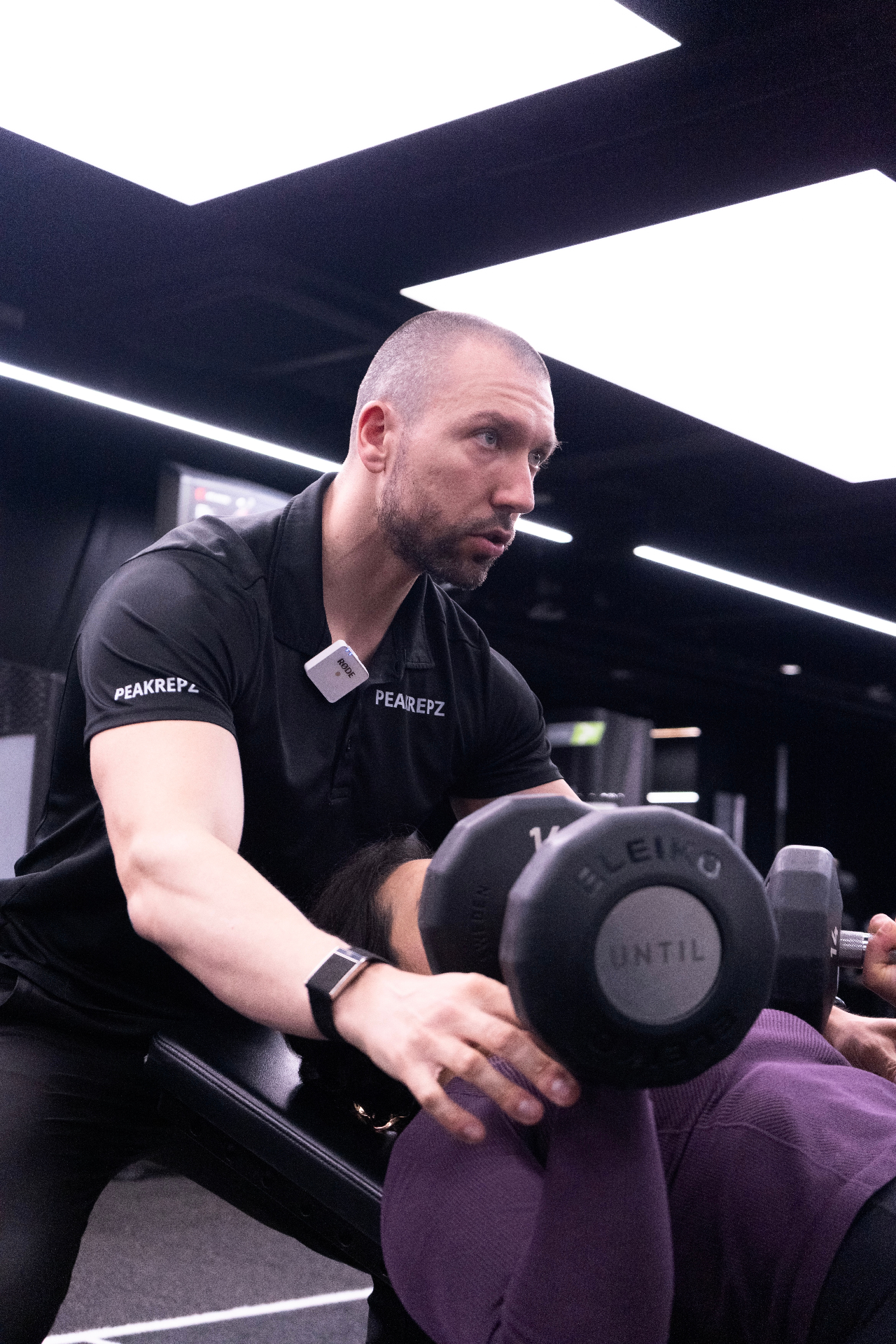Peakrepz coach guiding a client through a dumbbell press exercise
